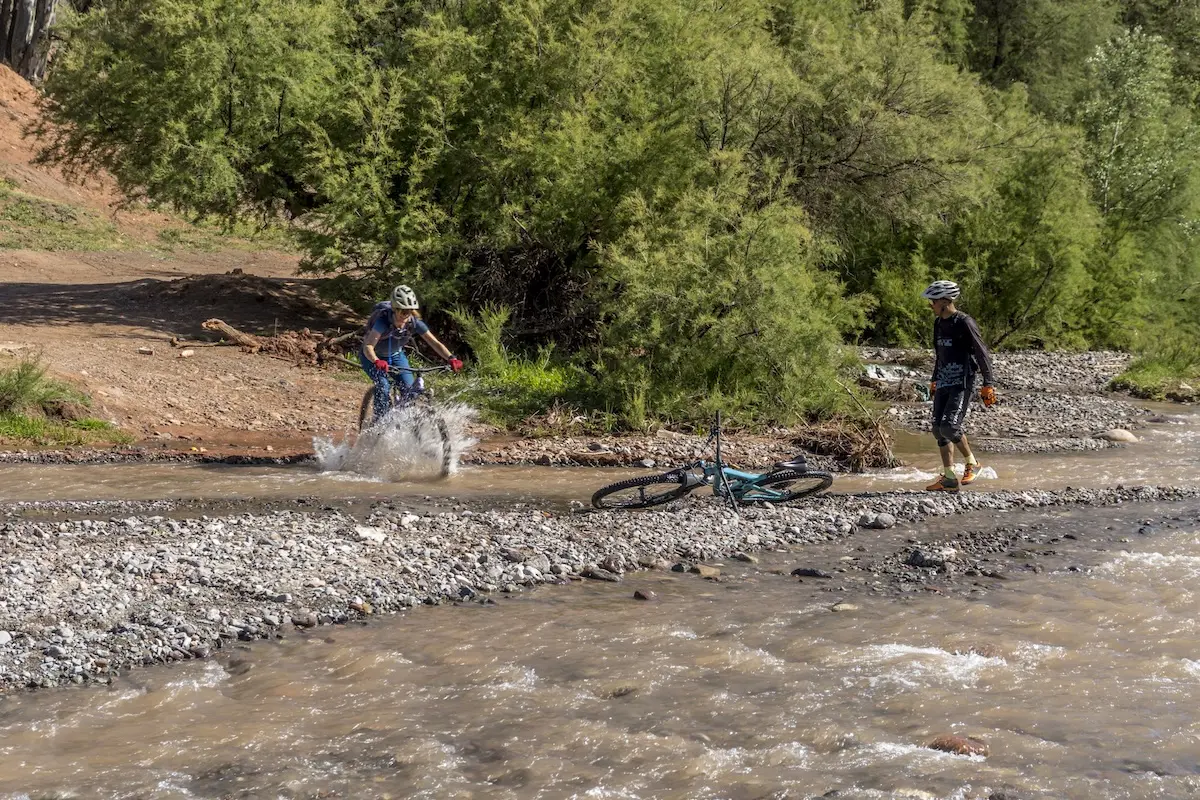 Female mountain biker riding through stream in Morocco