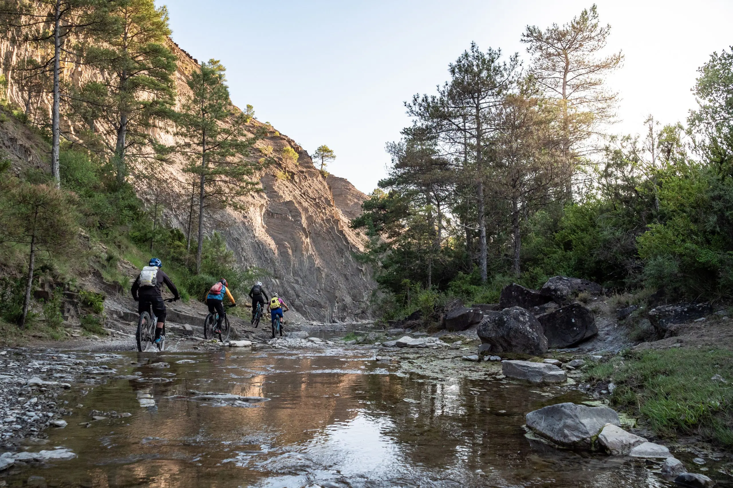 Mountain bikers riding through a river in the Pyrenees